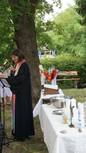 Pfarrerin Bindseil mit Altar mit weißem Tischtuch, darauf Taufkerzen und Taufschale im Garten
