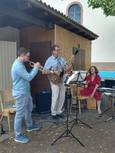 Band aus Trompeter, Gitarrist und Frau mit Trommel im Kirchgarten der Petruskirche