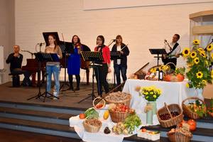 Lobpreisband auf der Bühne neben den Körben mit Obst und Gemüse für Erntedank